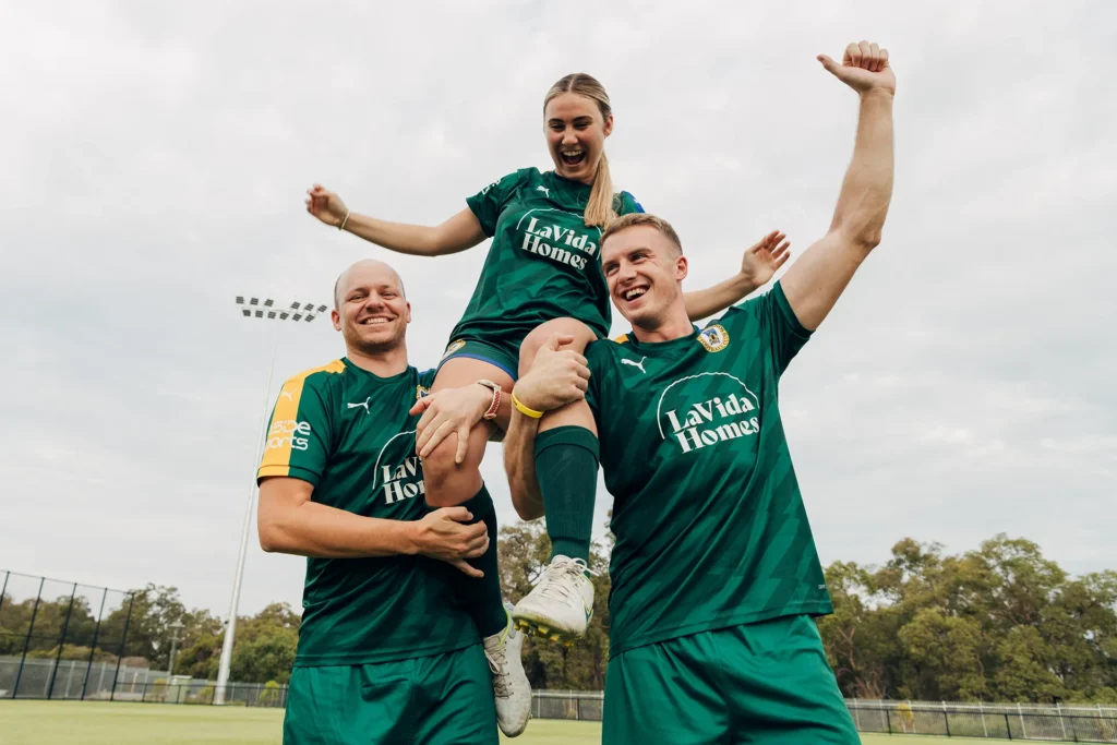 Soccer players hoisting player onto their shoulders